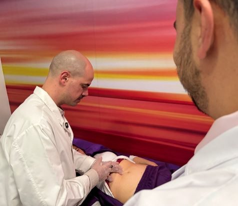 Doctor realizando procedimiento en paciente mientras otro le observa aimi medicine
